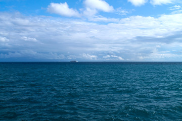 Blue sea, cloudy sky and ships on horizon