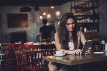 Business woman using tablet and drinking coffee in a cafe.