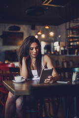 Business woman using tablet and drinking coffee in a cafe.