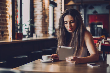 Business woman using tablet and drinking coffee in a cafe.