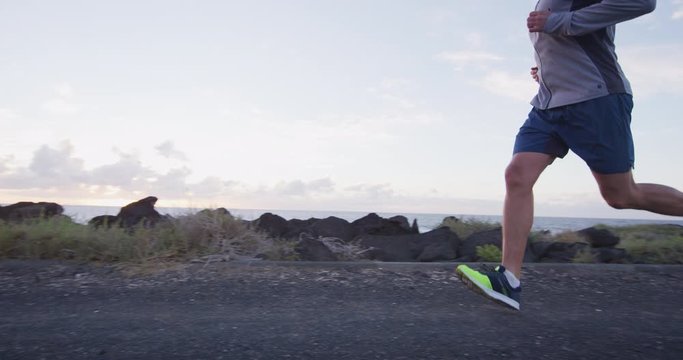 Man runner running on road at in slow motion. Male athlete in 30s on training run wearing running shoes and clothing