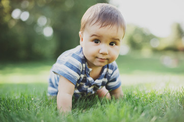 7 month child crawls on grass in yard,
