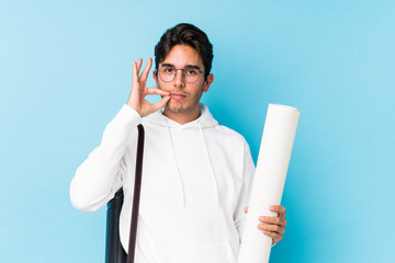 Young caucasian man studying architecture isolated with fingers on lips keeping a secret.