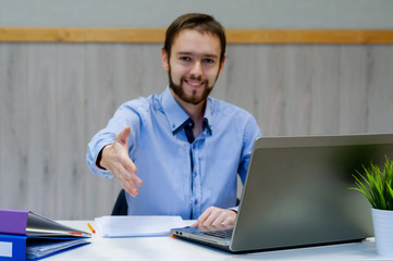 Smiling businessman stretching hand for handshake in office