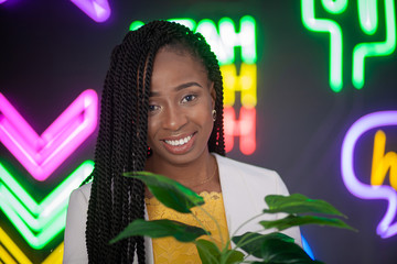 African-American girl sitting on a background of neon signs on a black background. Beautiful young...
