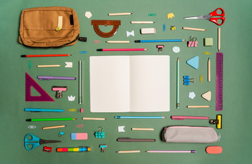 School stationery on green background. The concept banner with student supplies for back to school with pencils case, notes, paper clips, pins, sharpener, scissors, pencils and other tools. Mockup.