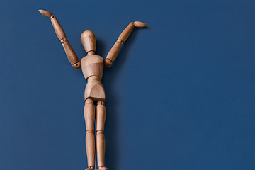 The wooden man figurine on a blue background.