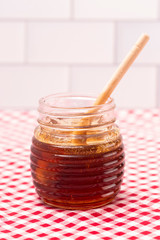 Jar of Fresh Raw Organic Honey on a Red and White Table Cloth