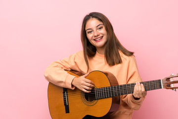 Young brunette girl with guitar over isolated pink background