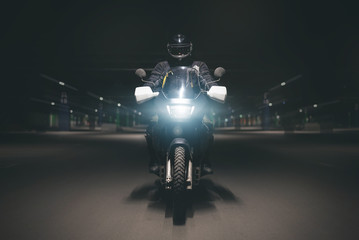 Motorcyclist is riding his motorbike on night parking road.