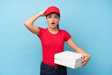 Young woman holding a pizza over isolated pink wall with surprise facial expression