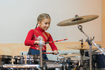 Teen girl playing the drums. Teen girls are having fun playing drum sets in music class. Girl in...