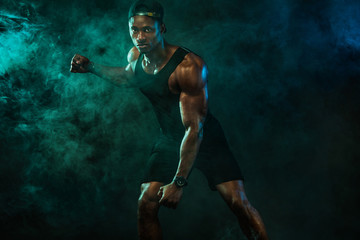 Fototapeta na wymiar Sports men athlete on dark background. Power athletic guy bodybuilder doing fitness training.