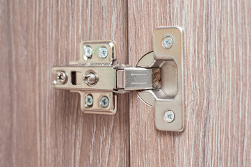 The hinge of the kitchen hinged bedside table that holds the wooden door. Kitchen fittings and...