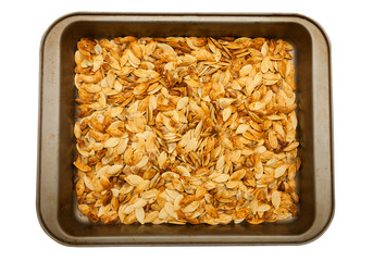 crispy home made pumpkin seeds baked in tray. isolated on white