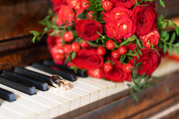 Stylish wedding bouquet of red roses on the piano. Wedding details.