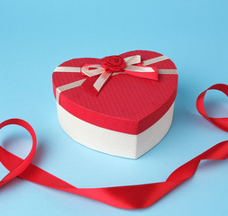 closed red heart-shaped gift box with a bow on a blue background
