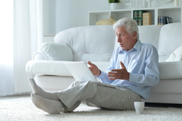 Emotional senior man using laptop at home