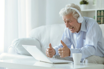 Fototapeta na wymiar Emotional senior man using laptop at home