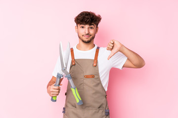 Young arab gardener man isolated showing a dislike gesture, thumbs down. Disagreement concept.