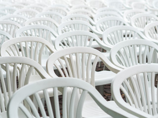 Lots of white plastic chairs. Abstract background.Selective focus. Image of a bunch of white plastic deck chairs.