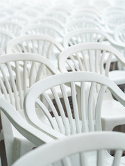 Lots of white plastic chairs. Abstract background.Selective focus. Image of a bunch of white plastic deck chairs.