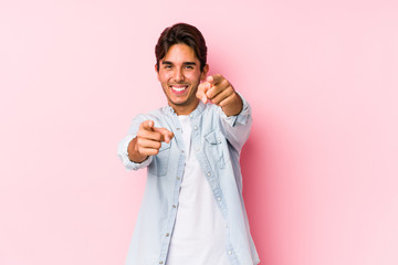 Young caucasian man posing in a pink background isolated cheerful smiles pointing to front.