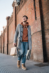 Young man holding shopping bags while walking on the street.