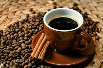  Brown Italian coffee cup on a saucer with pieces of cinnamon. The composition is located on the right of the image and grains of coffee are scattered around
