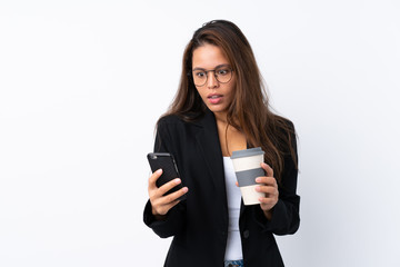 Fototapeta premium Young business Brazilian girl with mobile and holding coffee to take away over isolated background