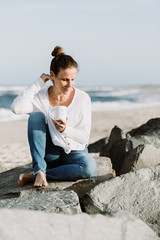 Woman Sitting By The Ocean Holding A Coffee Cup and Smiling, Relaxed Yoga Lifestyle Concept