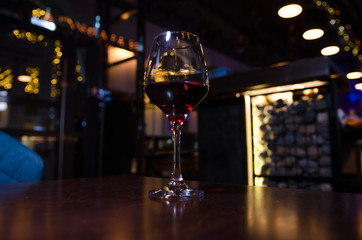 A glass of red wine on a dark bar background