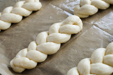 Fototapeta na wymiar Preparation process - raw unbaked buns. Homemade traditional pigtail buns on baking paper.