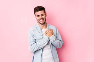 Young caucasian business man posing in a white background isolated laughing keeping hands on heart, concept of happiness.< mixto >