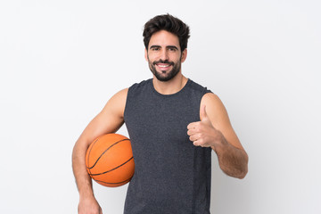 Young handsome man with beard over isolated white background playing basketball and with thumb up