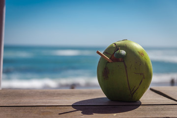 Coconut with a tube on the windowsill. Ocean view. Coconut water drink