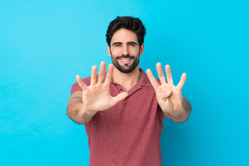 Young handsome man with beard over isolated blue background counting nine with fingers