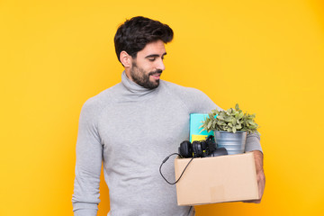 Young handsome man with beard making a move while picking up a box full of things over isolated...