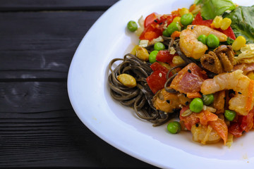 Tasty soba pasta with seafood and vegetables on wooden table