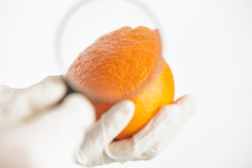 Scientist examining orange through magnifying glass