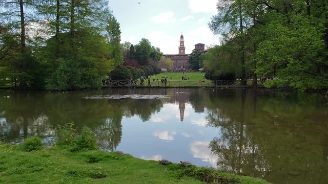 Milan, Italy - April, 2019 - Wide shot of Simplon Park (Parco Sempione) with a duck in the foreground and Sforza Castle (Castello Sforzesco) in the background.