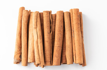 Cinnamon sticks lined up in a row on white background.