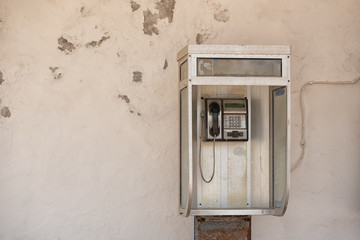 Fototapeta na wymiar Vintage pay public use phone cabin on white ragged wall