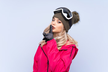 Skier teenager girl with snowboarding glasses over isolated blue background doing silence gesture