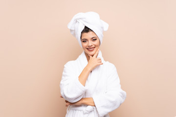 Teenager girl in a bathrobe over isolated background laughing