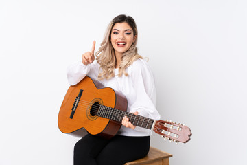 Fototapeta premium Teenager girl with guitar over isolated white background pointing up a great idea