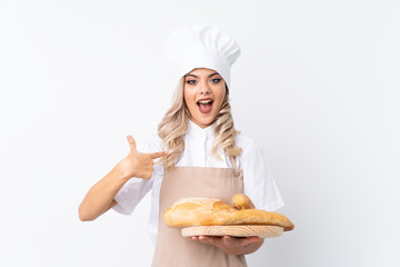 Teenager girl in chef uniform. Female baker holding a table with several breads over isolated white background with surprise facial expression