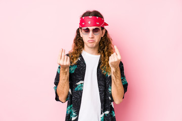 Young long hair hippie man posing in a pink background showing that she has no money.