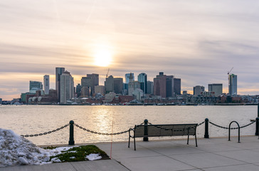 Metal Bench Overlooking Sunset Behind Downtown Boston With Overcast Skies