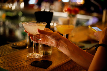 A girl holds a glass in her hand near the bar